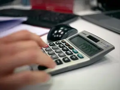 Persona utilizando calculadora para análisis de consumo energético en oficina