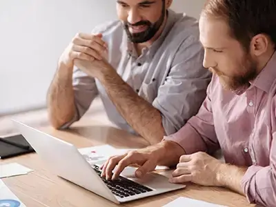 Consultores revisando propuestas técnicas frente a una notebook durante una reunión